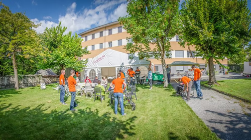 Bénévoles en t-shirt orange installant les tables et les fauteuils dans le jardin de Notre-Dame-du-Silence.